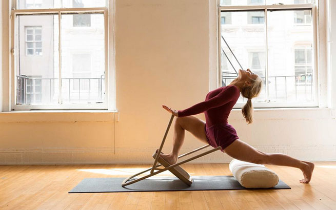 Iyengar Yoga wird mit Hilfsmitteln wie Stuhl und Kissen ausgeführt